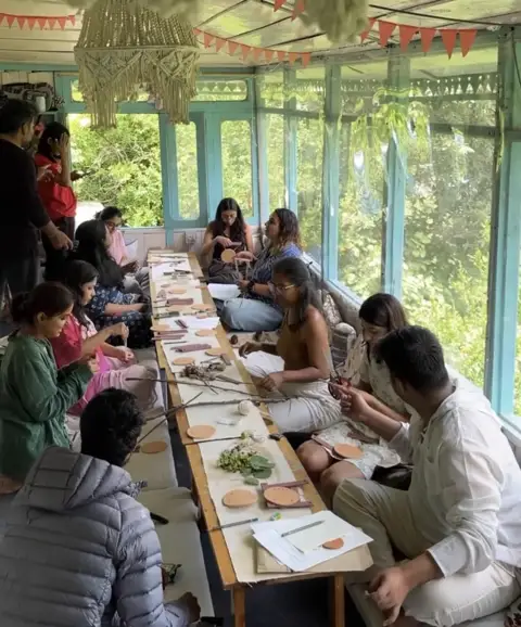 Guests hand-building around a long table in the glass verandah