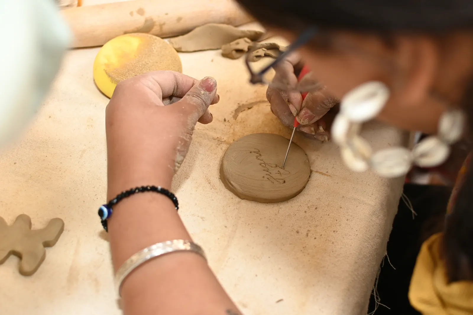 Slab of clay being rolled and textured on a canvas table