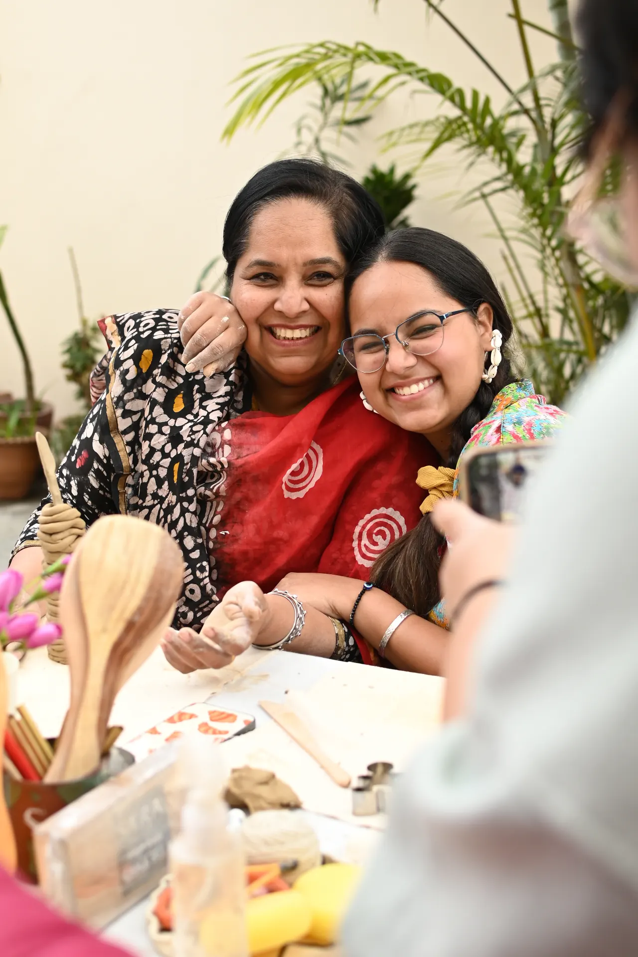 Two makers laughing, cheek to cheek, at the hand-building table