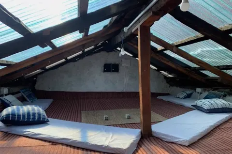 The attic loft at The Nook, mattresses laid out under the tin roof