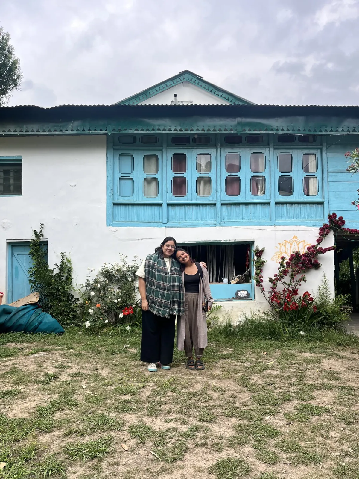 Two guests outside the blue-windowed Himachali house at The Nook