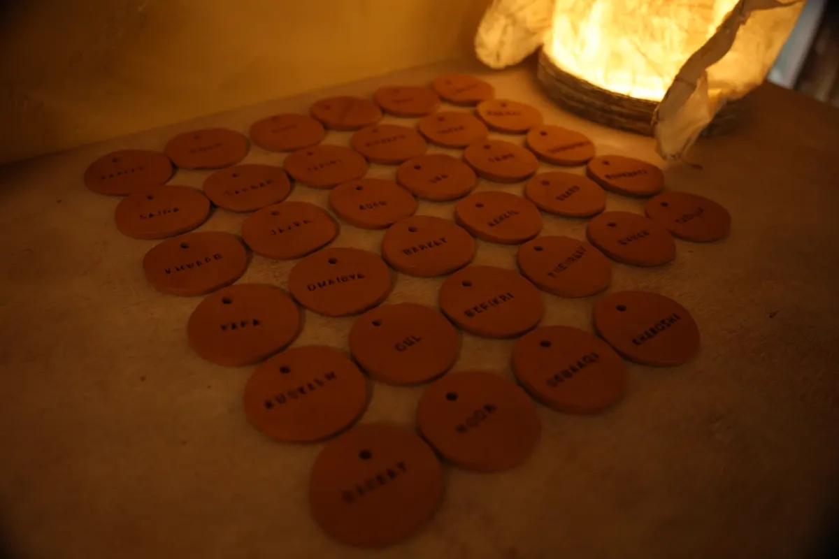 Hand-stamped clay name tags drying under a paper lamp