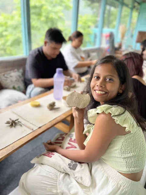 A guest smiling with the clay piece she just carved in the glass verandah
