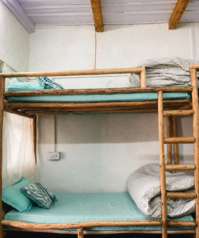 The bunk room at The Nook, log beds made up in sea-green linen