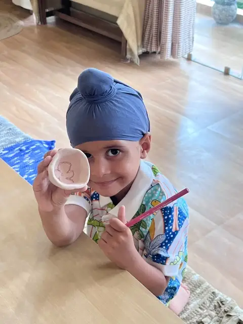 A little maker holding up a small pinch dish he decorated